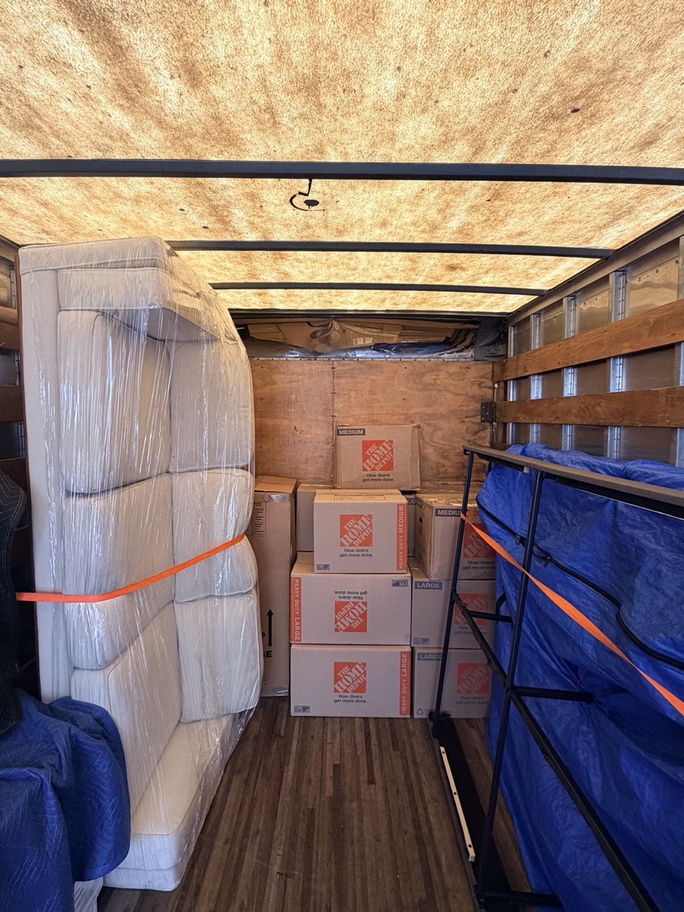 A wrapped mattress and stacked moving boxes arranged inside a box truck.
